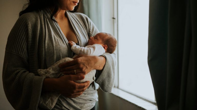 Mother holding her baby indoors