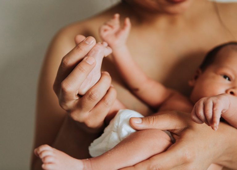 Naked mother holding her infant baby