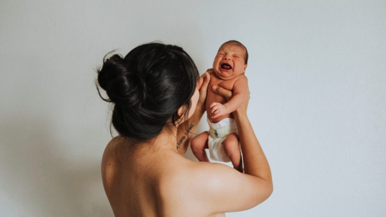 Naked mother holding her infant baby