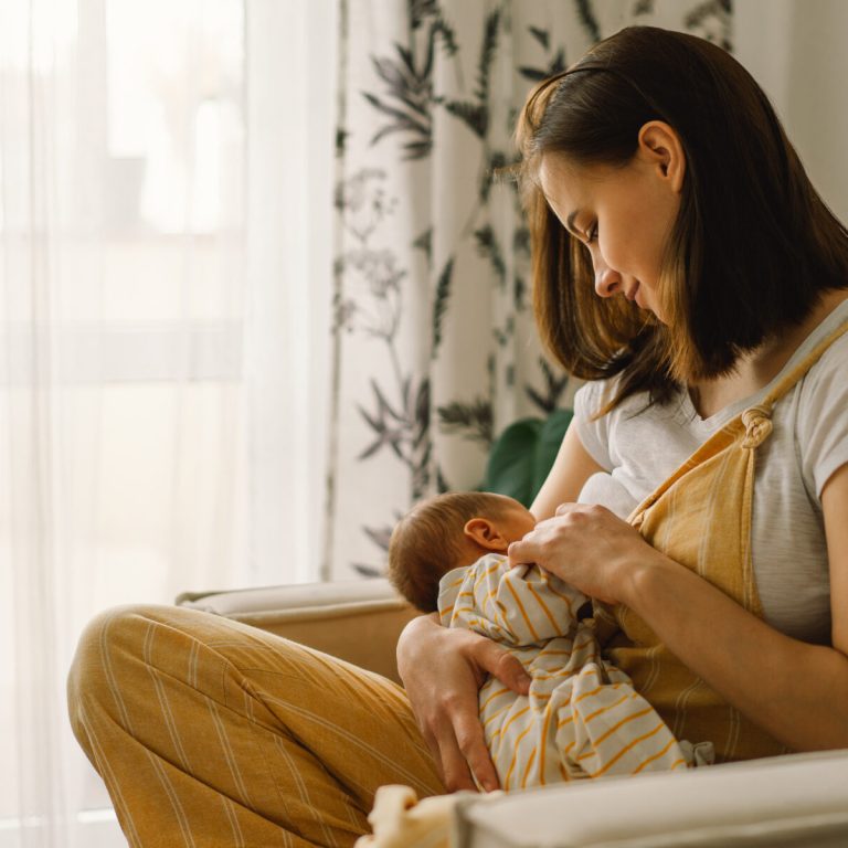 Newborn baby boy sucking milk from mothers breast. Portrait of mom and breastfeeding baby. Concept of healthy and natural baby breastfeeding nutrition.